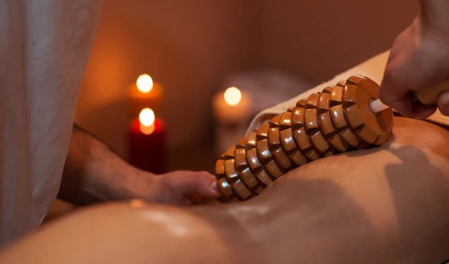 Maderoterapia Masaje relajante con piedras calientes y velas encendidas en un ambiente tranquilo.